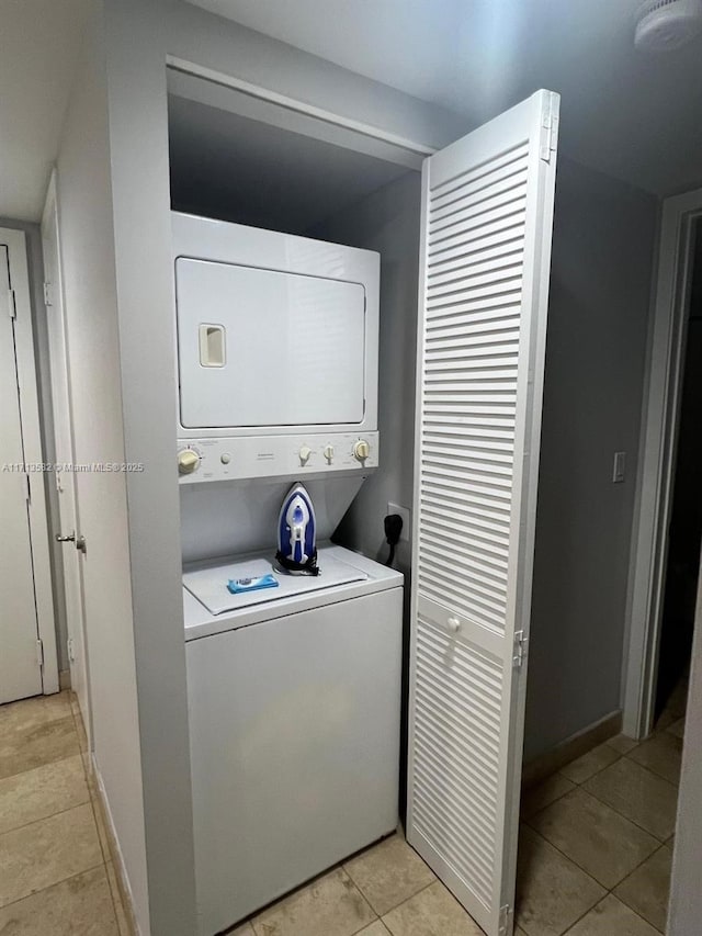 laundry area with stacked washer / dryer and light tile patterned floors