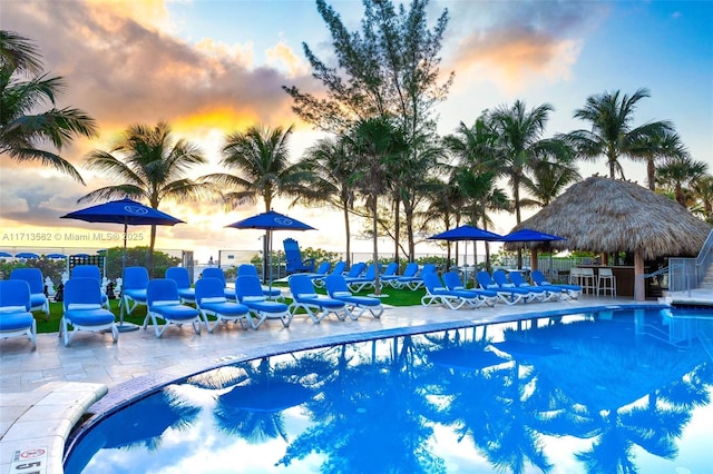 pool at dusk featuring a gazebo and a patio area