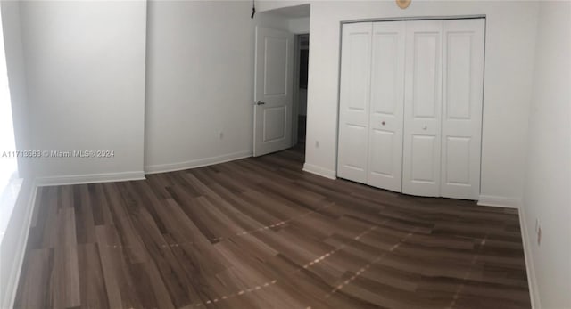 unfurnished bedroom with dark hardwood / wood-style floors and a closet