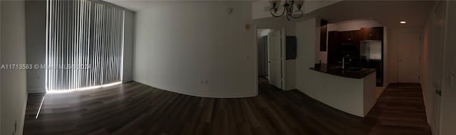 empty room featuring dark hardwood / wood-style flooring, a notable chandelier, and sink