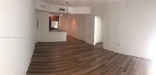 empty room featuring a notable chandelier and dark hardwood / wood-style floors