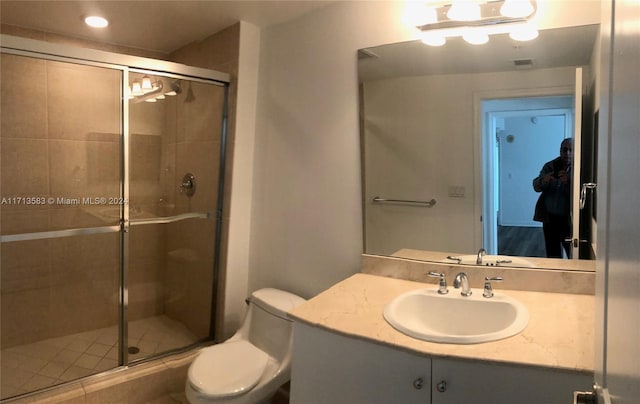 bathroom featuring vanity, toilet, and a shower with shower door