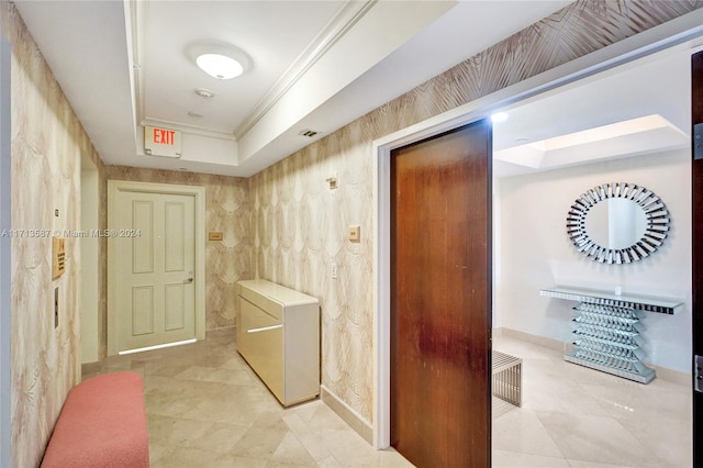 hallway with a raised ceiling and crown molding