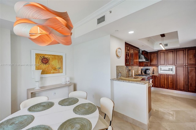 kitchen featuring wall chimney range hood, stainless steel appliances, tasteful backsplash, sink, and a raised ceiling