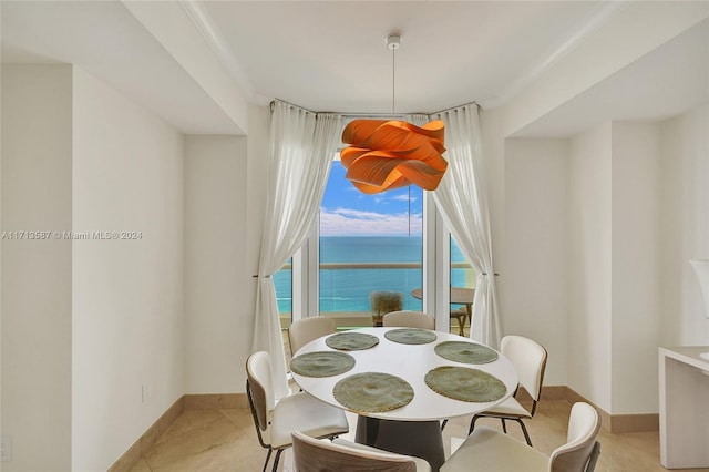 tiled dining room with a water view and ornamental molding