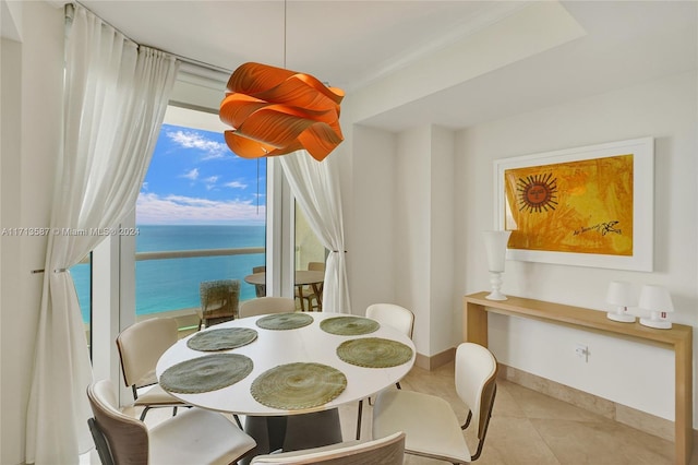 dining area featuring light tile patterned floors and a water view