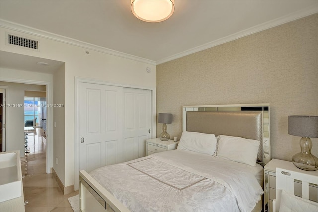 bedroom with a closet, crown molding, and light tile patterned flooring