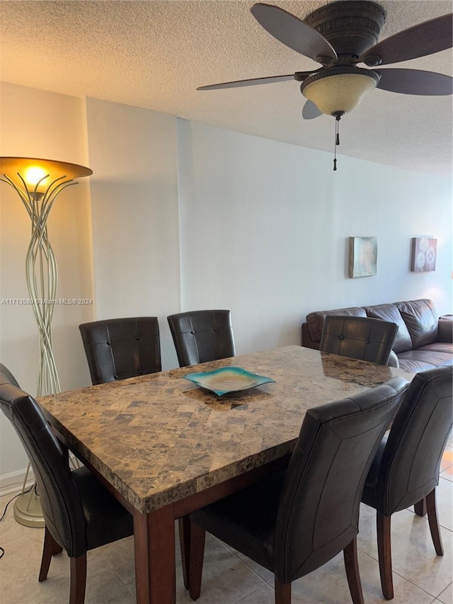 tiled dining space with ceiling fan and a textured ceiling