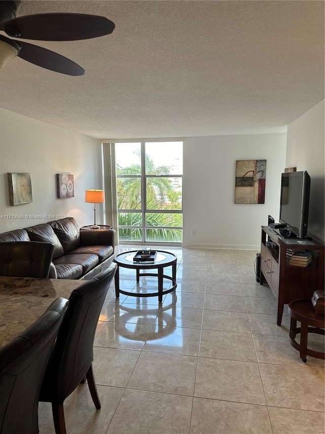 tiled living room with ceiling fan, floor to ceiling windows, and a textured ceiling