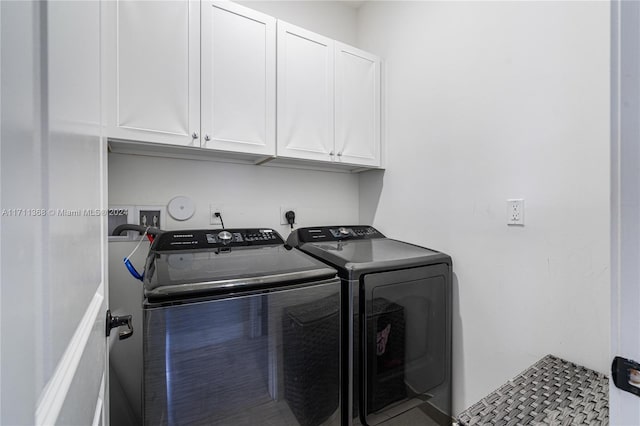 clothes washing area with washer and dryer and cabinets