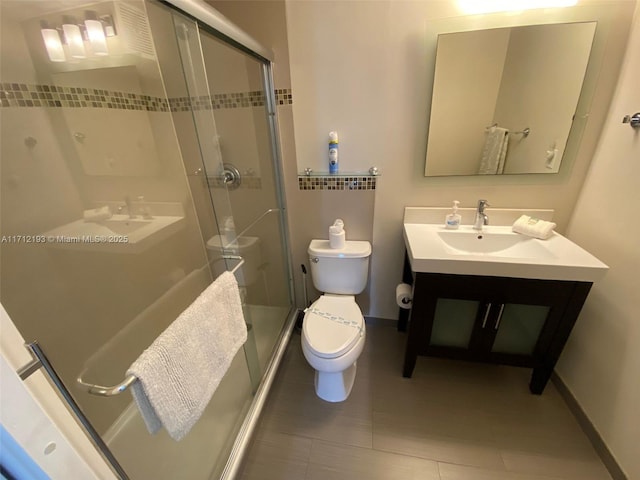 bathroom featuring a stall shower, baseboards, toilet, tile patterned flooring, and vanity