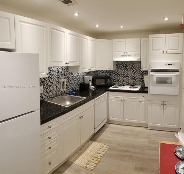 kitchen with dark countertops, white appliances, white cabinetry, and under cabinet range hood