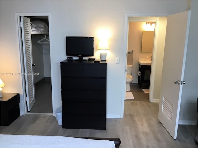 bedroom featuring light wood-style flooring, baseboards, and a closet