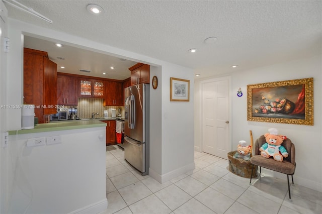 kitchen featuring stainless steel refrigerator, sink, backsplash, kitchen peninsula, and light tile patterned flooring