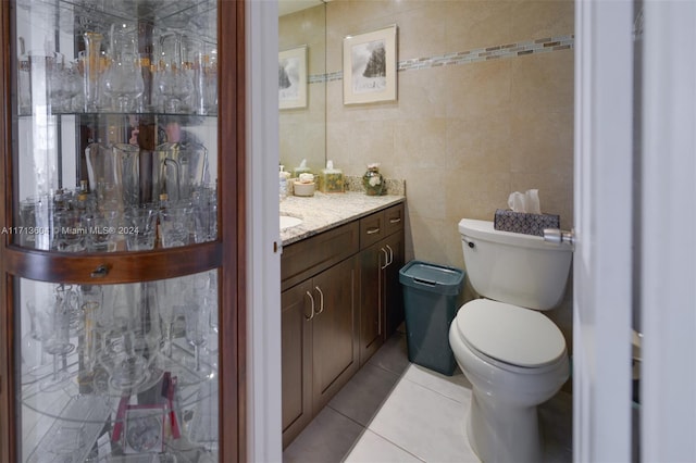 bathroom with tile patterned floors, vanity, tile walls, and toilet