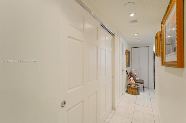 hall featuring light tile patterned floors and a textured ceiling