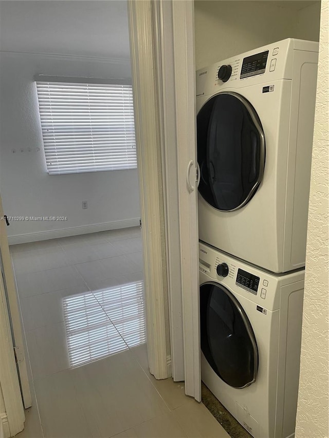 laundry room featuring stacked washing maching and dryer and light tile patterned floors