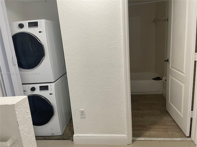 laundry area with light tile patterned floors and stacked washer and clothes dryer