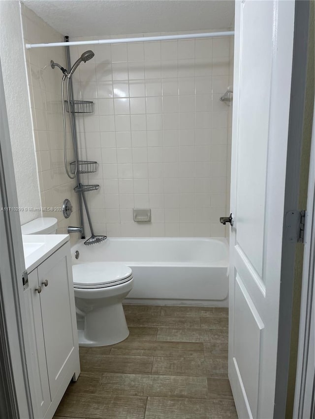 full bathroom featuring tiled shower / bath, vanity, and toilet