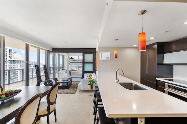 kitchen featuring dark brown cabinetry, sink, stainless steel oven, decorative light fixtures, and black electric cooktop