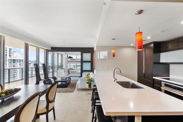 kitchen with appliances with stainless steel finishes, sink, light tile patterned floors, and decorative light fixtures