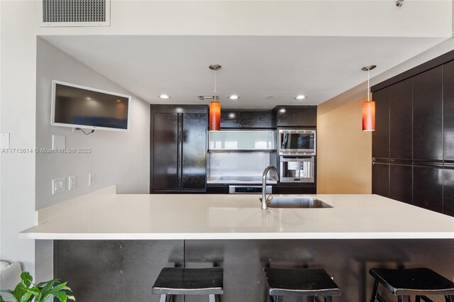 kitchen featuring sink, pendant lighting, stainless steel appliances, kitchen peninsula, and a breakfast bar area