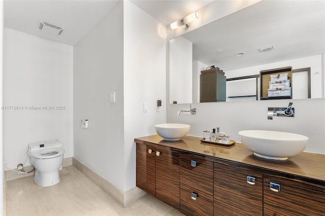 bathroom with toilet, vanity, and tile patterned flooring