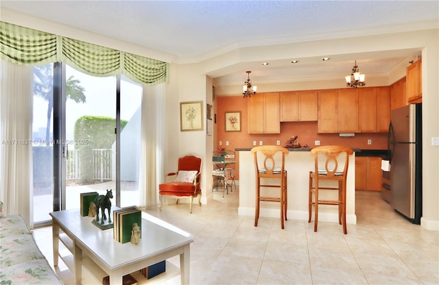 kitchen featuring freestanding refrigerator, hanging light fixtures, crown molding, and a notable chandelier