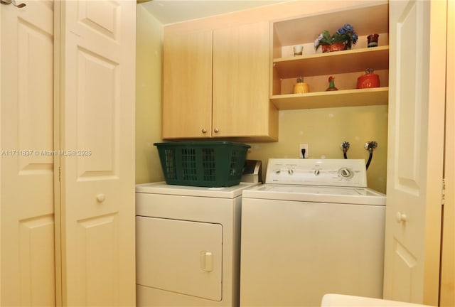 clothes washing area with cabinets and washing machine and dryer