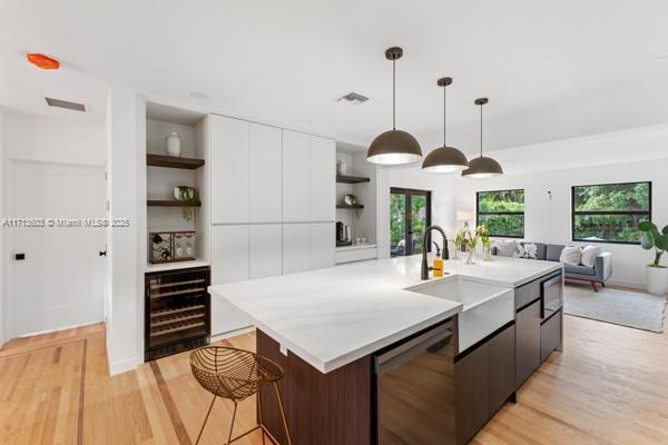 kitchen with open shelves, beverage cooler, modern cabinets, light wood-type flooring, and light countertops