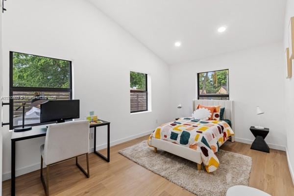 bedroom with high vaulted ceiling and light wood-type flooring