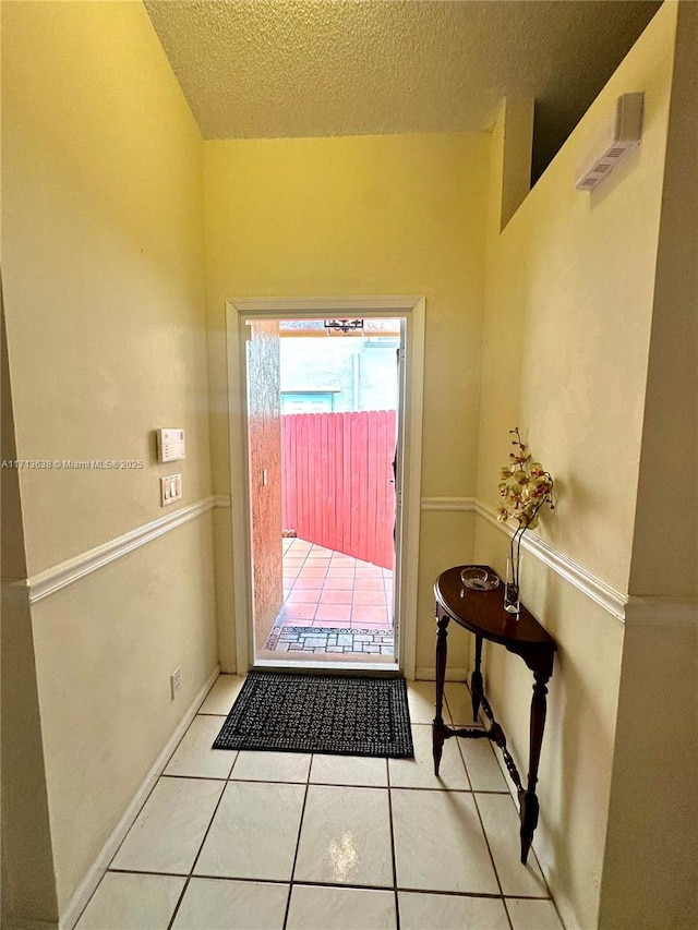 doorway to outside featuring a textured ceiling and light tile patterned flooring