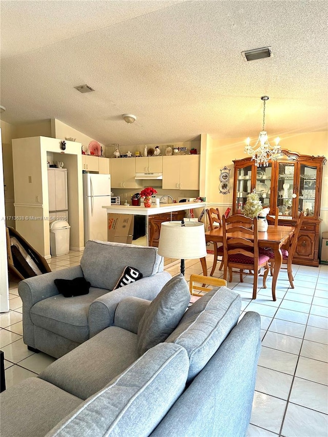 tiled living room with a textured ceiling, vaulted ceiling, and a notable chandelier