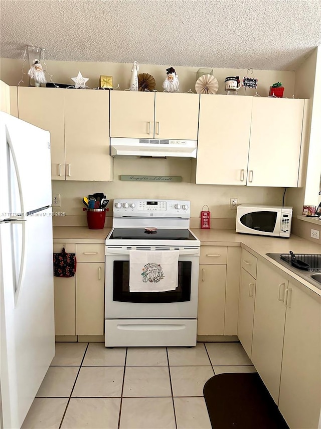 kitchen with cream cabinets, white appliances, and light tile patterned flooring