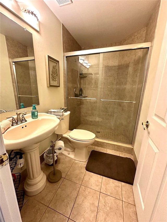 bathroom featuring tile patterned flooring, toilet, and an enclosed shower