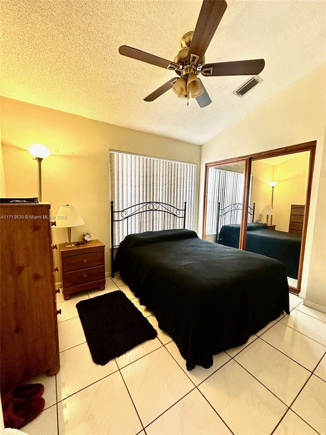 bedroom featuring a textured ceiling, ceiling fan, light tile patterned flooring, and lofted ceiling