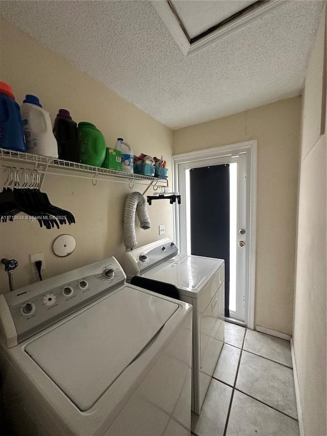 washroom featuring washer and clothes dryer, light tile patterned floors, and a textured ceiling