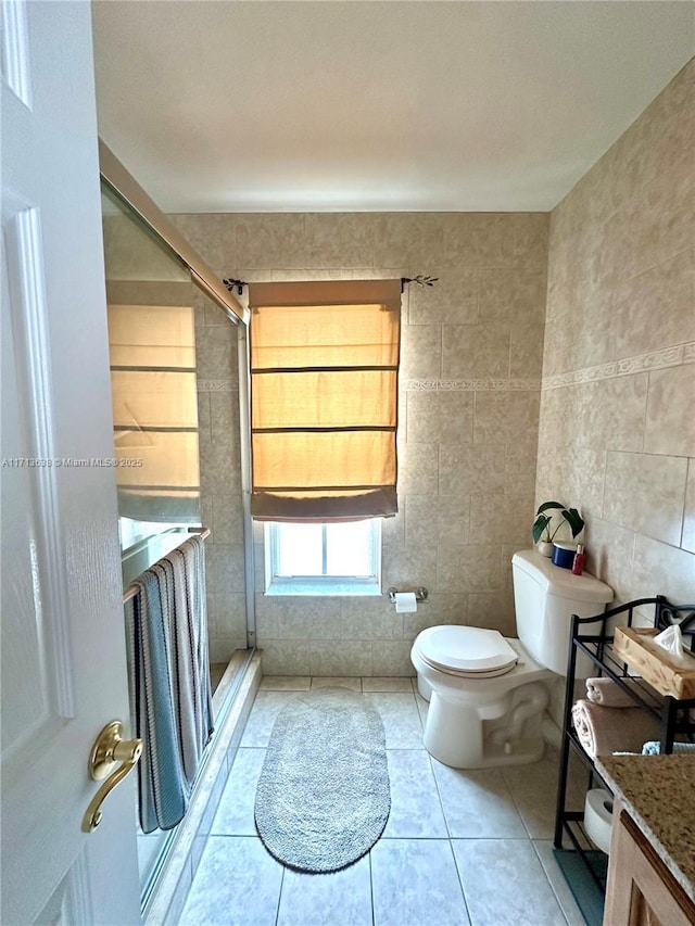 bathroom with vanity, tile patterned floors, toilet, walk in shower, and tile walls