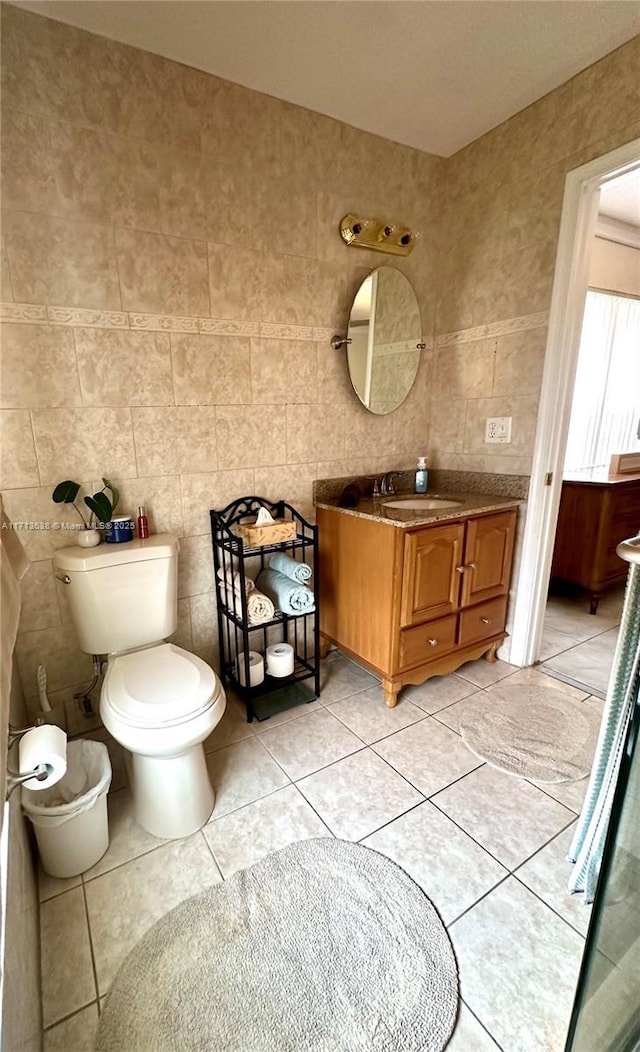 bathroom with tile patterned flooring, vanity, toilet, and tile walls