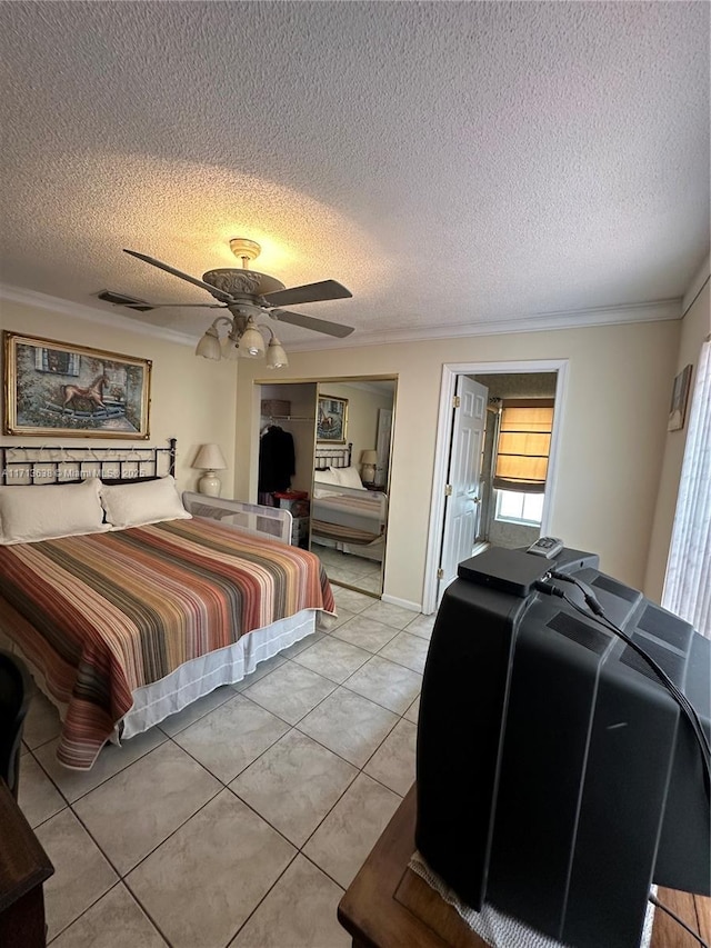 tiled bedroom featuring ceiling fan, a textured ceiling, and ornamental molding