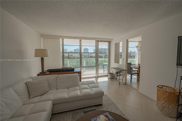 living room with light tile patterned floors, a textured ceiling, and a wall of windows