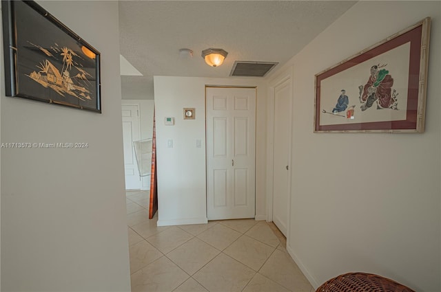 corridor featuring light tile patterned flooring and a textured ceiling