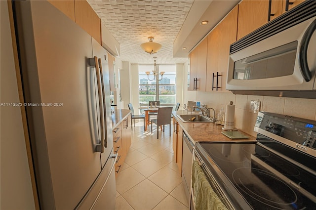 kitchen featuring sink, hanging light fixtures, a chandelier, light tile patterned flooring, and appliances with stainless steel finishes