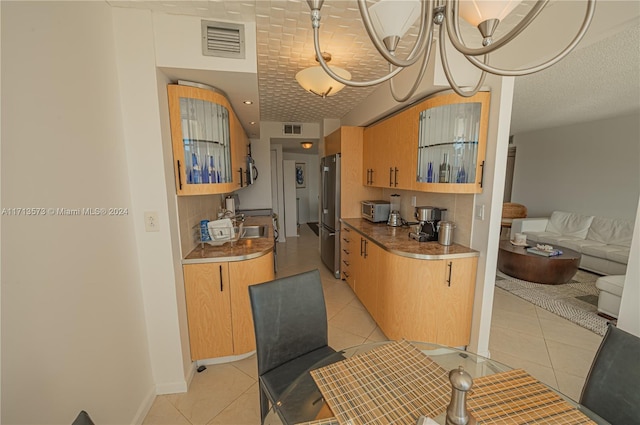 kitchen with stainless steel refrigerator, a notable chandelier, and light tile patterned flooring