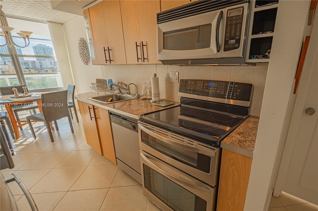 kitchen featuring light tile patterned flooring, stainless steel appliances, tasteful backsplash, and sink