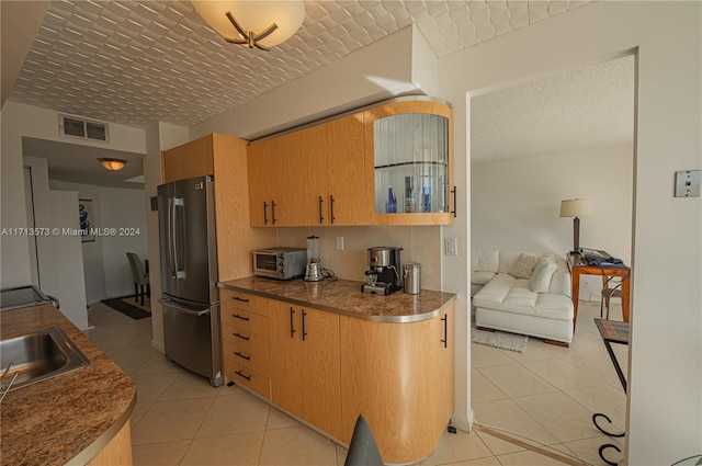 kitchen with stainless steel refrigerator, sink, and light tile patterned flooring