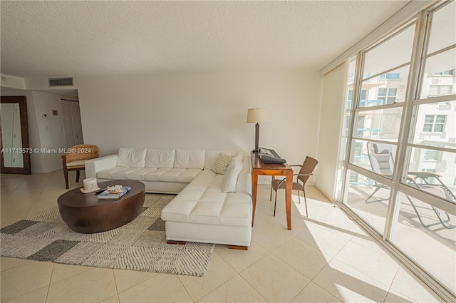 tiled living room featuring floor to ceiling windows and a textured ceiling