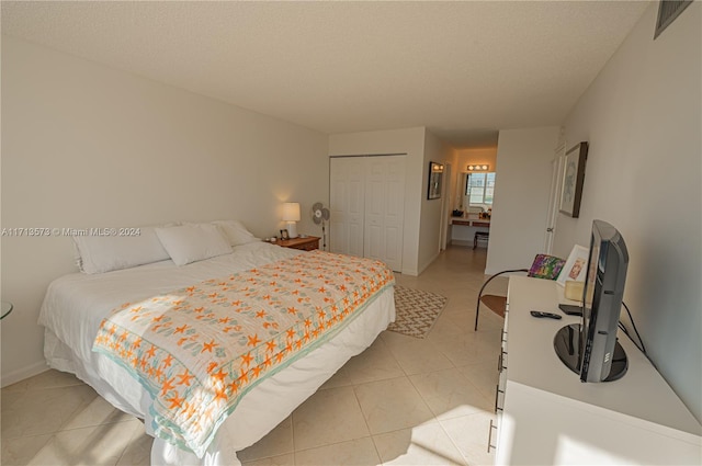 bedroom with light tile patterned floors, a textured ceiling, and a closet