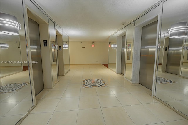 hallway with light tile patterned floors and a textured ceiling