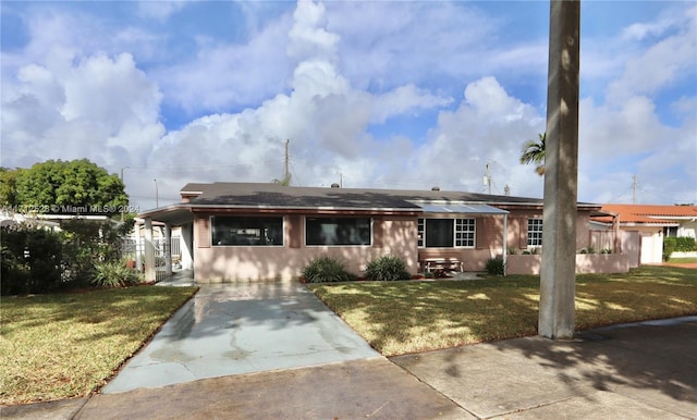 view of front of home with a carport, solar panels, and a front yard